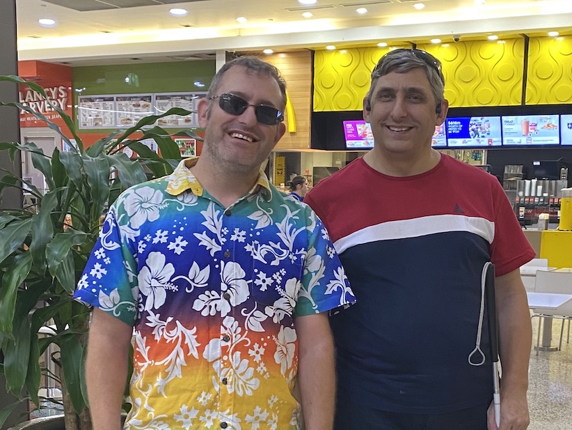 Two men in bright shirts in a food dining environment.