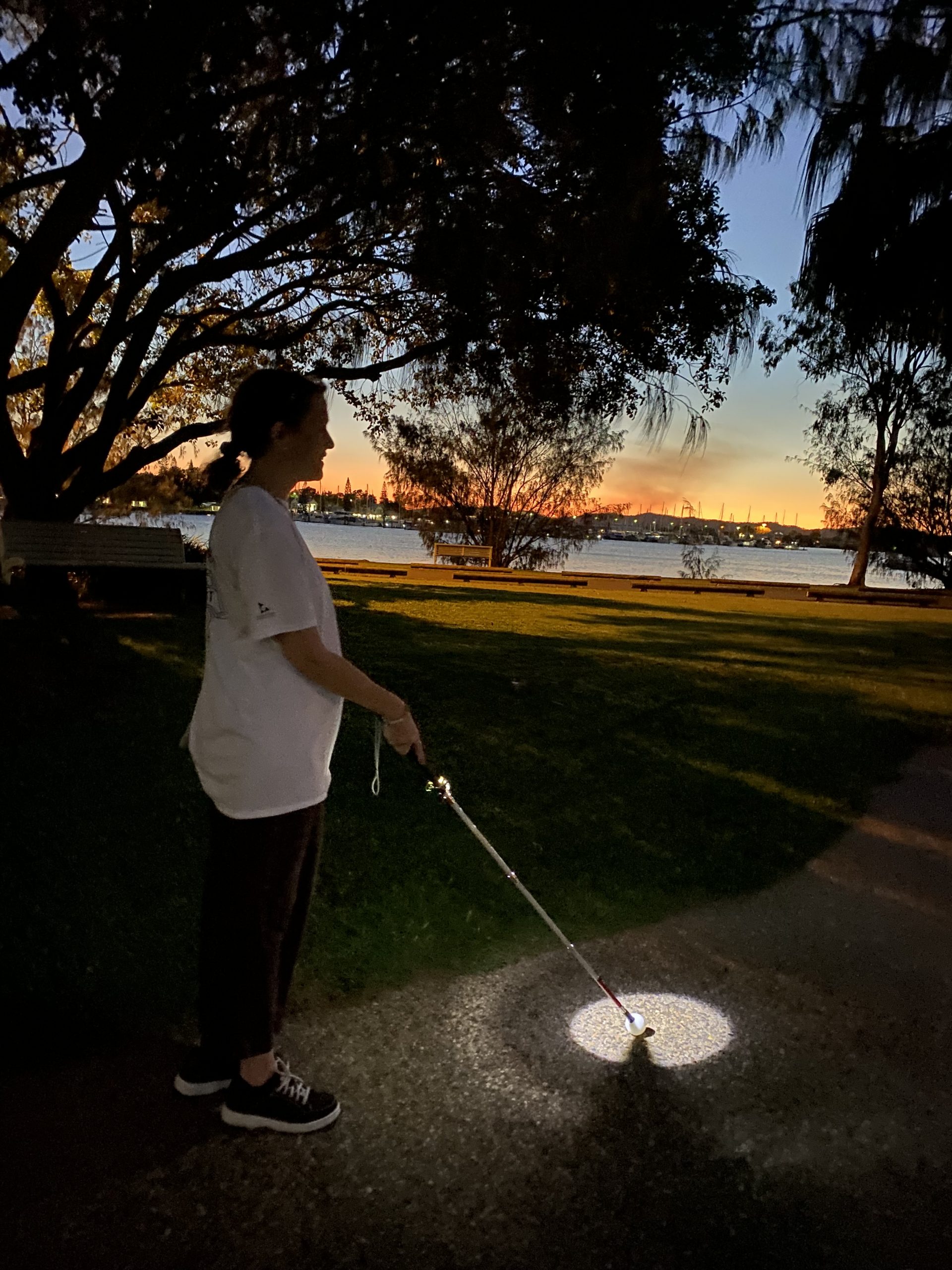 Client in Gladstone using the Ambutech Pharos Cane Light at dusk